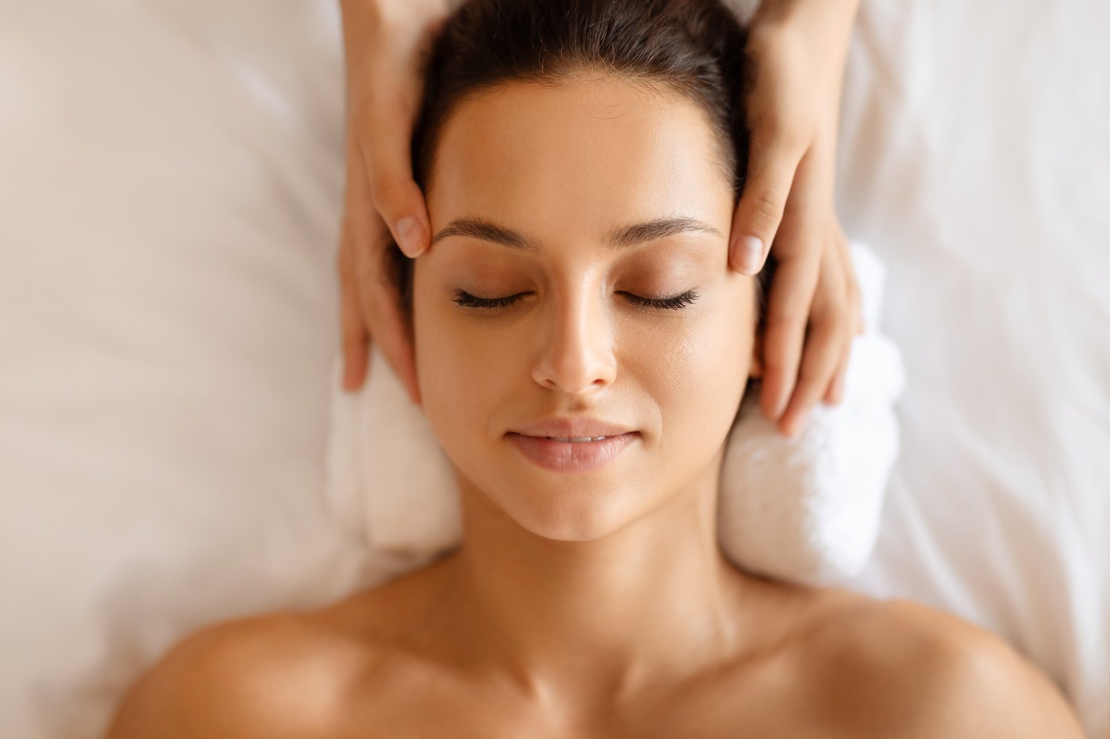 European lady getting healing head massage from masseuse at spa